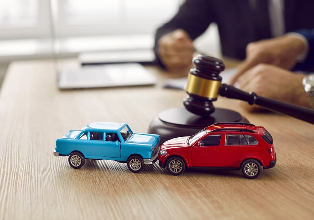 Blog 3 Gavel and two small toy car models on desk in courthouse.